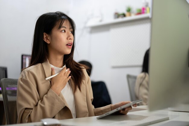 A beautiful amazed Asian businesswoman is surprised with an unexpected email on her computer