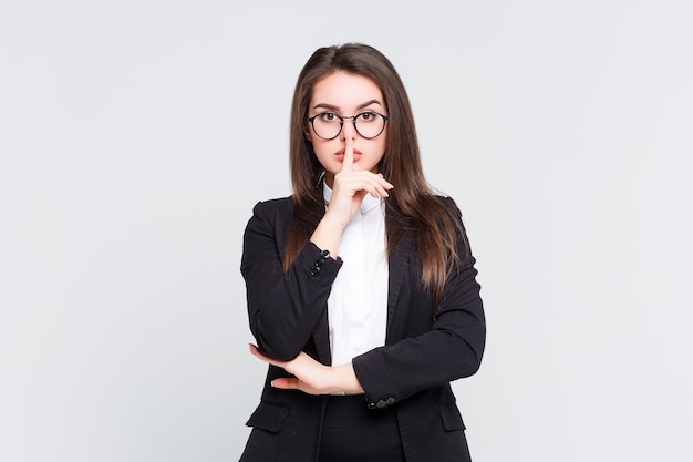 Beautiful amazed female model dressed at black suit isolated over white wall