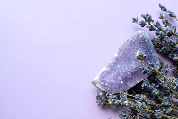 A beautiful amethyst druse with a dry bouquet of lavender on a lilac background Magic amulets