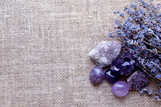 Beautiful amethyst stones and amethyst druze with a dry bouquet of lavender against a background of coarse burlap fabric Magic amulets Sopy space