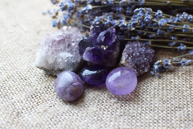 Beautiful amethyst stones and amethyst druze with a dry bouquet of lavender against a background of coarse burlap fabric Magic amulets