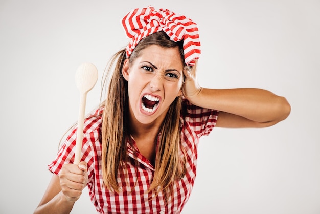 Beautiful anger girl holding mixed spoon. Looking at camera.