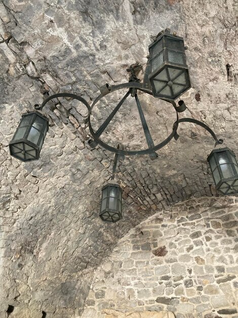 Фото Красивая старинная люстра для улицы, в которую вставлены свечи. висит на каменном потолке