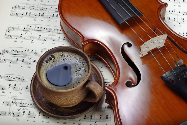 beautiful antique violin on a background of notes and cup of coffee