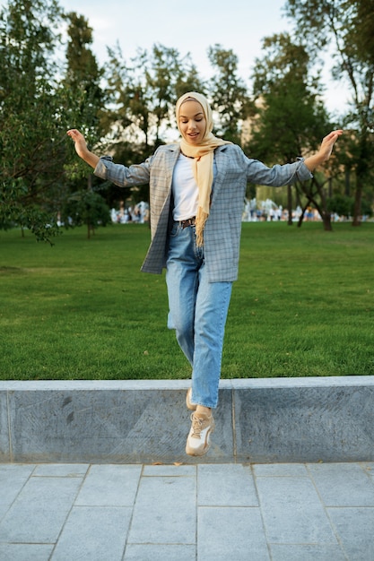 Hijab에서 아름 다운 아랍 여성 학생 여름 공원에서 포즈. 잔디밭에 쉬고 이슬람 여성입니다.