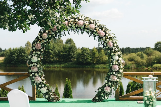 湖の景色を望む自然の風景に、結婚式のための美しいアーチ