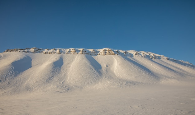 雪で美しい北極の冬の風景は、ノルウェーのスバールバル諸島の山々をカバー