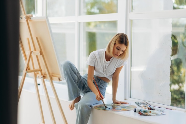 Beautiful artist in her studio Happy girl likes to draw Place for text