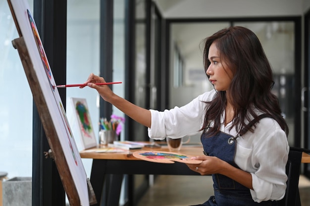 Beautiful artist painting on easel in art studio