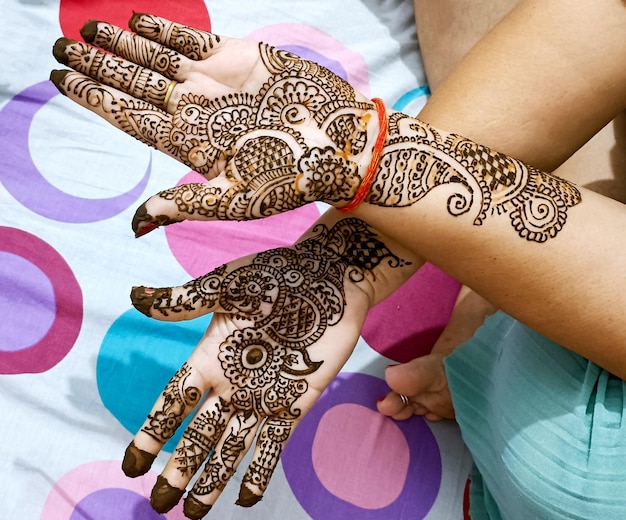 湿った状態でハーブのヒーナを持つインドの花嫁の手に描かれた美しいアートワーク