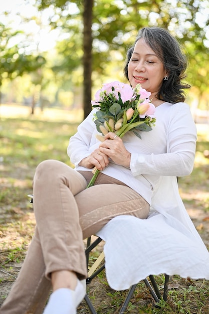 Beautiful Asian aged woman holding a beautiful flower bouquet relaxing in the park