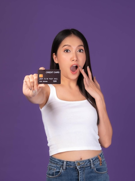 Beautiful Asian brunette woman cute girl in white tank top Excited surprised girlshowing credit card for payment shopping online credit card online shopping ecommerce telemarketing concept