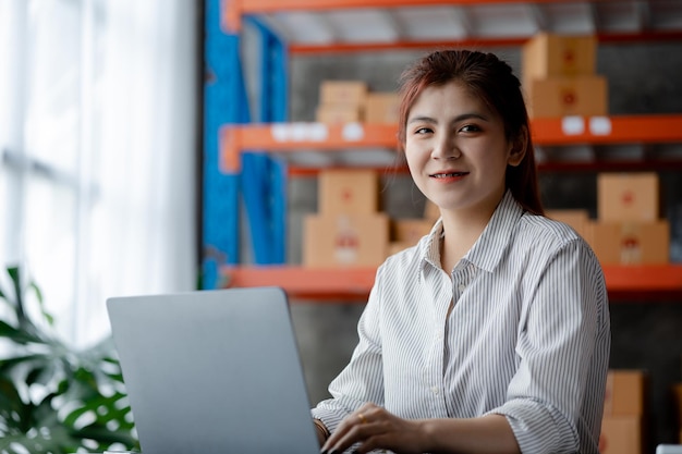 A beautiful Asian business owner opens an online store she is checking orders from customers sending goods through a courier company concept of a woman opening an online business