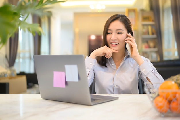 Una bella donna d'affari asiatica sta lavorando con il suo computer a casa, telecomunicazioni, allontanamento sociale, concetto di lavoro da casa.