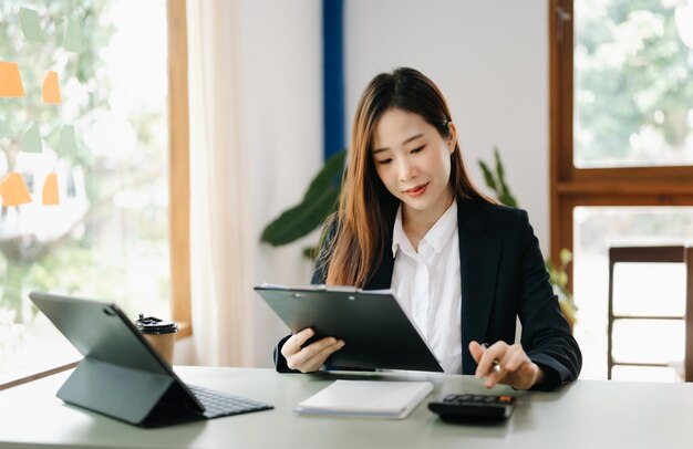 Beautiful Asian business woman typing laptop and tablet Placed at the table at the home office