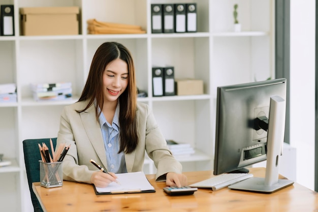 Beautiful Asian business woman typing laptop and tablet Placed at the table at the modern office