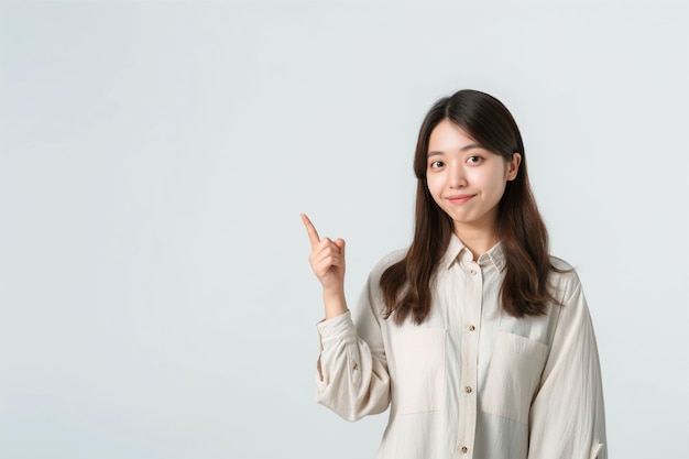 Photo beautiful asian business woman wearing shirt pointing at empty copy space and smiling isolated