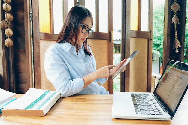 Beautiful asian business woman working with laptop, mobile phone, and tablet.