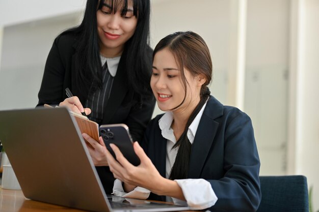 Beautiful Asian businesswoman at her desk discussing a project with her coworker