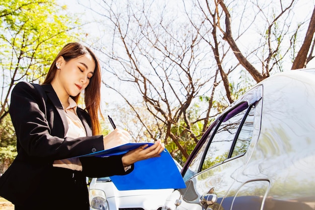 Beautiful asian businesswoman is responsible helping car\
insurance take note documents for evidence