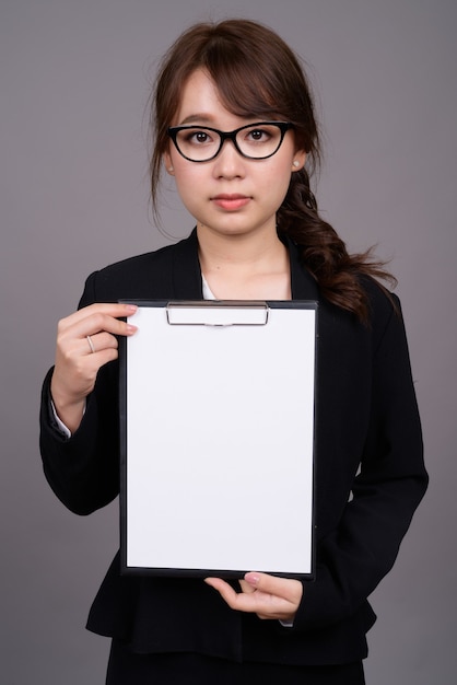 Beautiful Asian businesswoman showing copyspace in clipboard