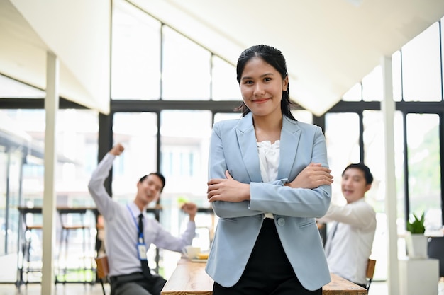 A beautiful Asian businesswoman stands in the meeting room with her arms crossed