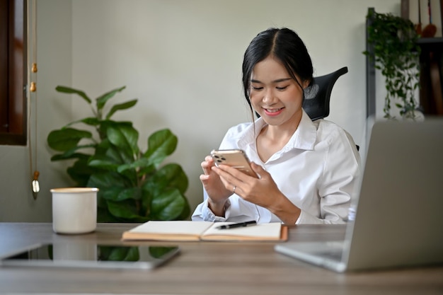 A beautiful Asian businesswoman texting with her friends on her smartphone