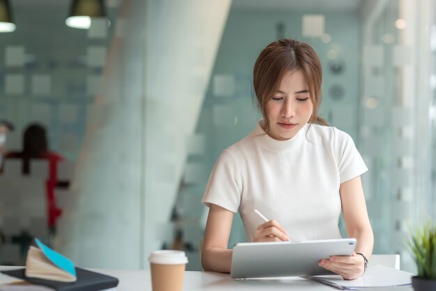 Beautiful Asian businesswoman working on a tablet at a modern office.