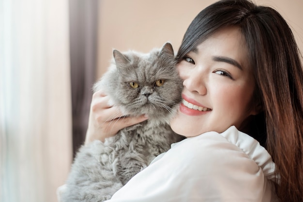 Beautiful asian cat lover woman is playing with cat in her room