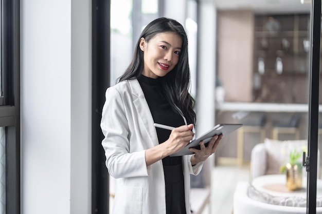 Beautiful asian doctor education profession doctor in white uniform gown coat professional medical doctor with tablet at seminar or hospital wellness center