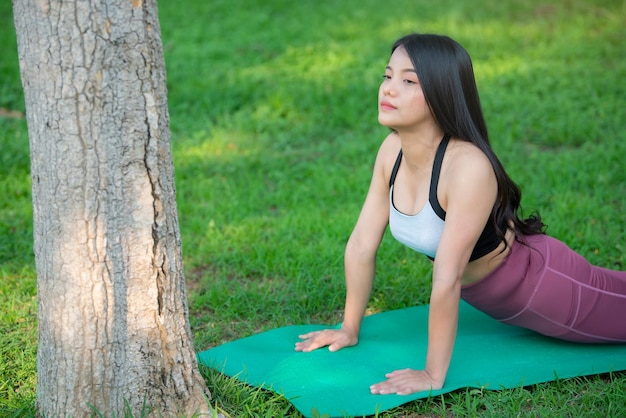 Красивая азиатская толстая женщина играет в йогу в парке. Нужно похудеть.