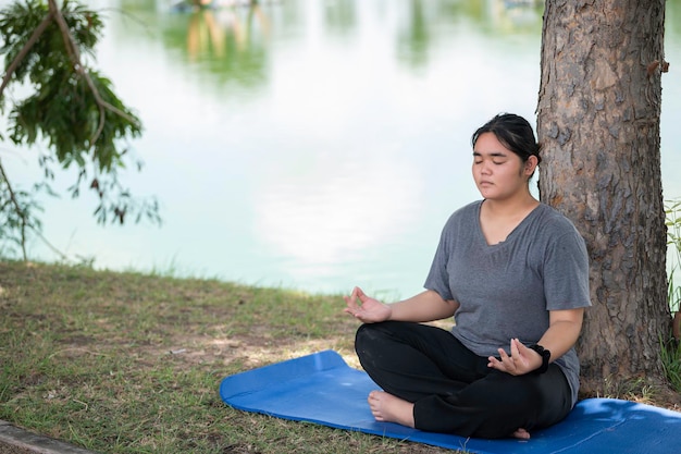 Beautiful asian fat woman play yoga at the parkNeed to slim fit body