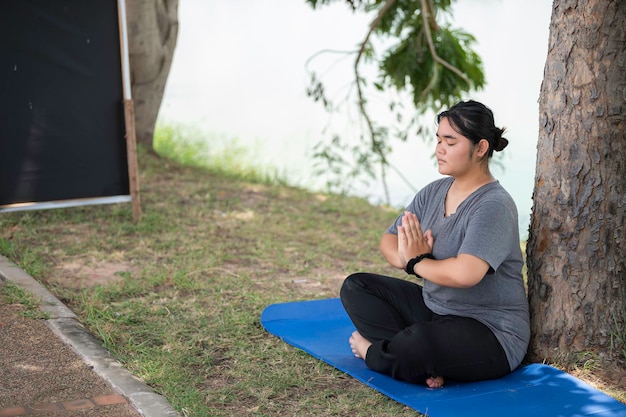 Beautiful asian fat woman play yoga at the parkNeed to slim fit body