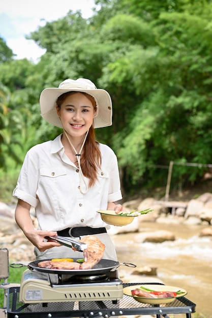 屋外のピクニックストーブで彼女の朝食を調理する美しいアジアの女性キャンピングカー旅行者