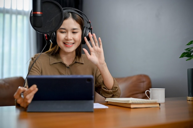 Beautiful asian female radio host running her radio show or\
podcasting at home studio