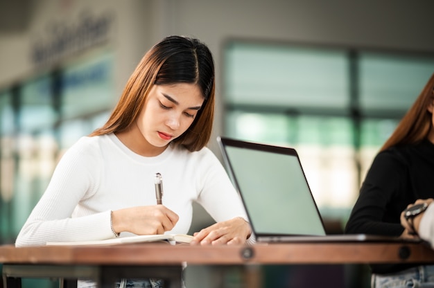 美しいアジアの女子学生が列教育ライフスタイル大学に座っている大学の教室の学生で試験のために座る