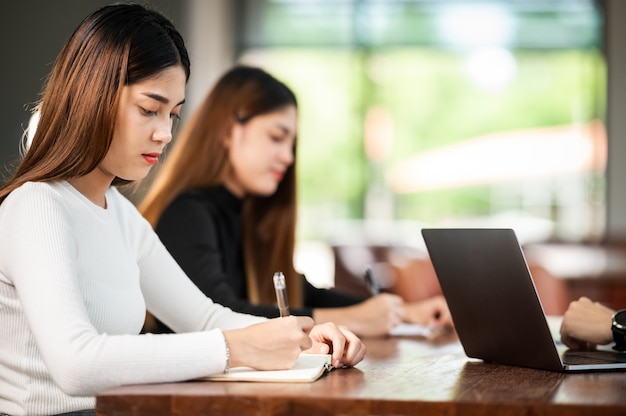 美しいアジアの女子学生が列教育ライフスタイル大学に座っている大学の教室の学生で試験のために座る