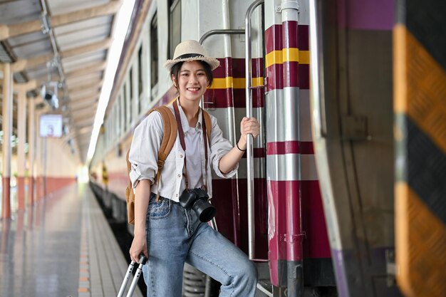 美しいアジア人の女性旅行者バックパッカーが駅で電車に乗っています