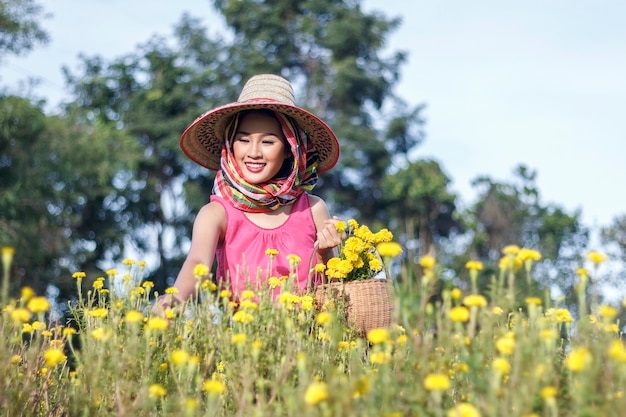 Foto bella ragazza asiatica del giardiniere nel giacimento di fiori del tagete