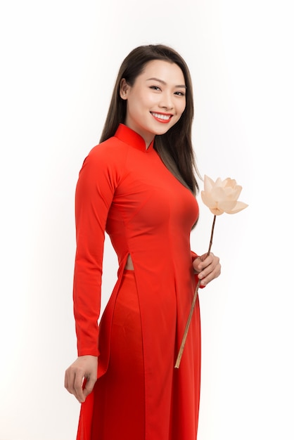 Красивая азиатская девушка в ао дай, держа на руке цветок лотоса