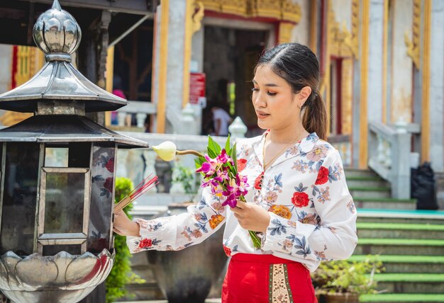 Красивая азиатская девушка в большом буддийском храме, одетая в традиционный костюм