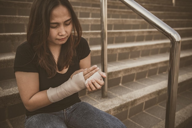 Foto una bella ragazza asiatica si è rotta il braccio e si è steccata. la donna cade accidentalmente con le braccia colpite a terra provocando fratture