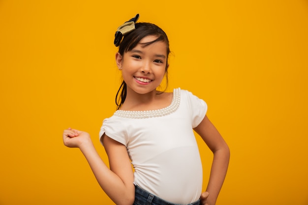 Beautiful asian girl sitting on yellow background