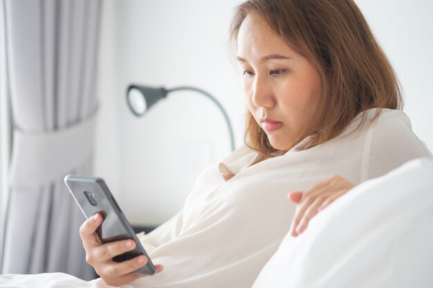 Beautiful Asian girl sleeping on a smartphone. Play on the media.