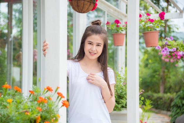 Красивая азиатская девушка, стоя в парке и улыбки на камеру