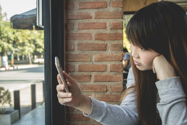 美しいアジアの女の子は、コーヒーショップ、ビジネスファイナンスの概念で電話を使用