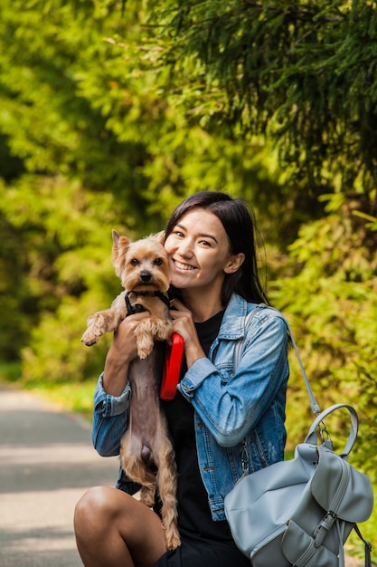 彼女の犬ヨークシャーテリアと一緒に夏に公園を散歩する美しいアジアの女の子