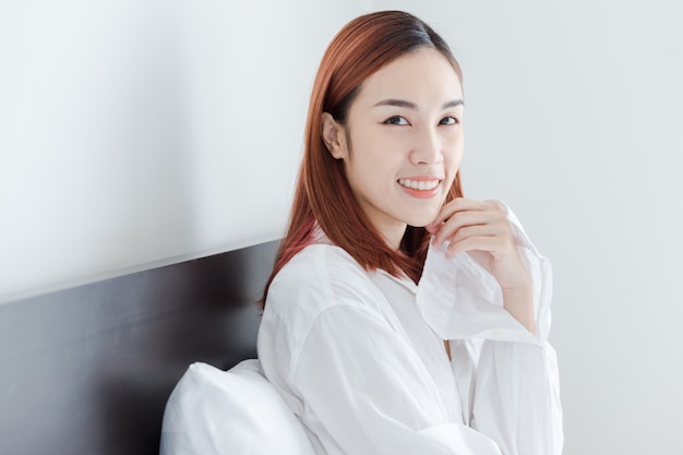 Beautiful Asian girl wear white shirt smile in her room at the morning