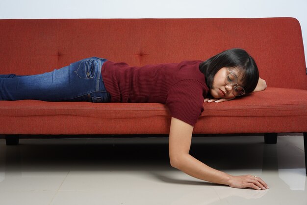 Photo beautiful asian girl wearing red shirt and blue jeans fall asleep on the couch