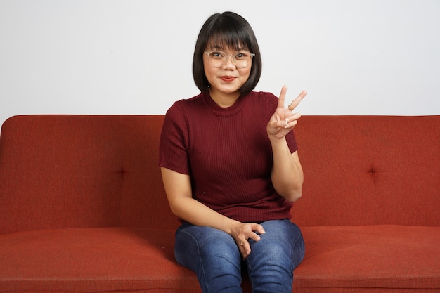 Beautiful Asian Girl Wearing red shirt and blue jeans Showing Victory Sign Peace Sign